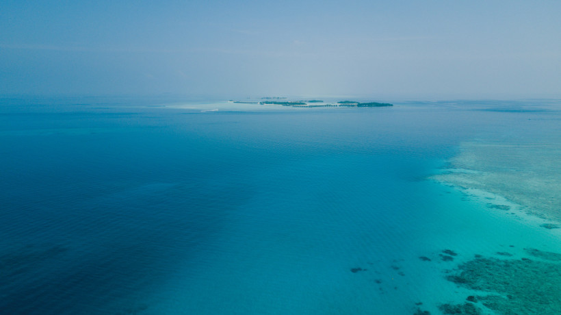 Malediven - Maafushi Blick auf eine kleine Inselgruppe der Malediven, umgeben vom türkisblauen Indischen Ozean. Die Inseln liegen in der Ferne und erscheinen wie grüne Punkte im weiten Meer.