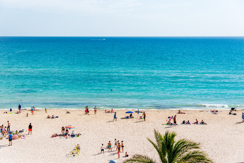 Blick auf den Sandstrand von El Arenal mit Familien und Badegästen am Meer