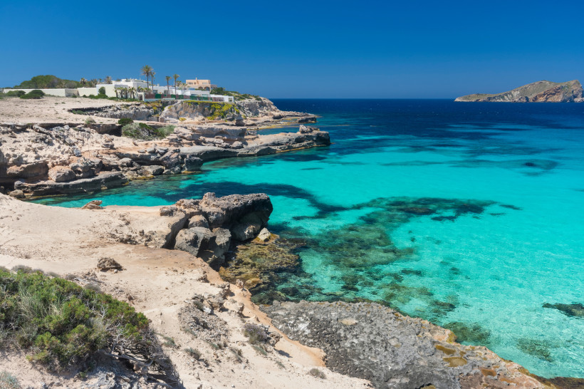 Felsige Küste an der Cala Comte mit türkisfarbenem Meer und klarer Bucht