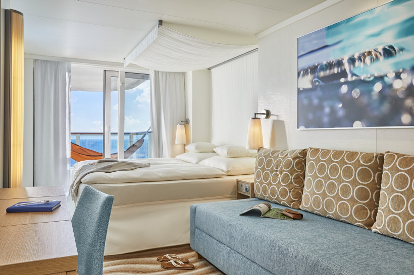 Deluxe-Verandakabine auf der AIDAnova mit Doppelbett, Sofa und Balkonblick aufs Meer