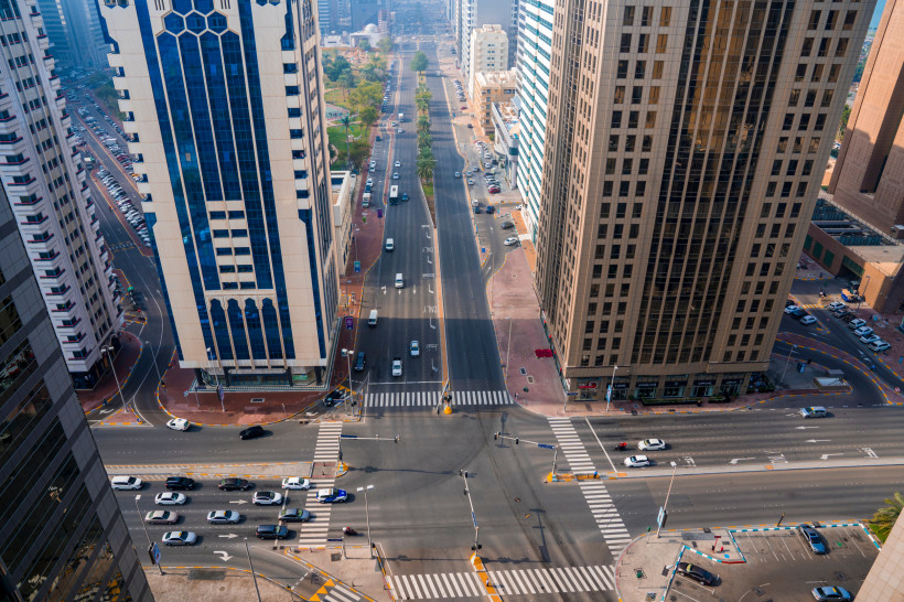 Luftaufnahme einer breiten Straßenkreuzung in Abu Dhabi, umgeben von hohen Wolkenkratzern und Autos auf der Straße