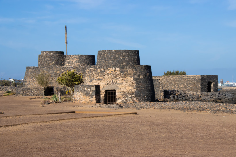 Castillo de San Buenaventura, Festung aus dunklem Naturstein mit runden Bastionen unter blauem Himmel