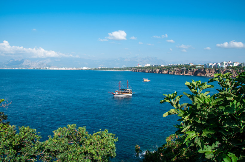 Bootstour an der Küste von Belek – Panorama auf Meer, Klippen und Taurusgebirge Ausflugsboot auf dem tiefblauen Meer vor der Küste von Belek mit Blick auf Klippen, Antalya und das Taurusgebirge.
