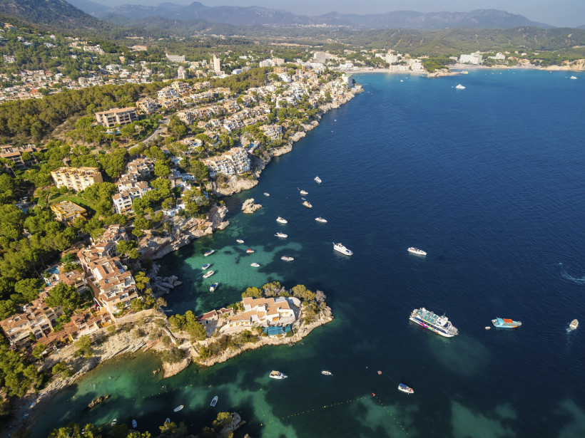 Luftaufnahme der Cala Fornells bei Paguera mit felsiger Küste, Wohnhäusern und Booten in einer türkisblauen Bucht