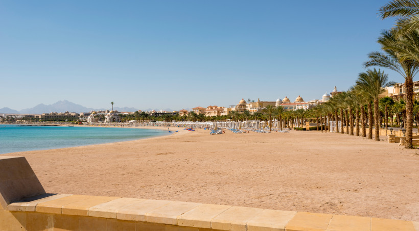 Sonniger Strand von Sahl Hasheesh mit Blick auf die Hotelanlagen Weiter Sandstrand von Sahl Hasheesh mit türkisblauem Meer, Palmenallee und eleganten Hotelanlagen im Hintergrund bei klarem Himmel
