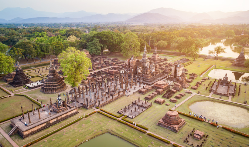 Sukhothai Historical Park – Luftaufnahme der Tempelruinen in Thailand Luftaufnahme des Sukhothai Historical Parks in Thailand mit historischen Tempelruinen, Chedis und grüner Landschaft.