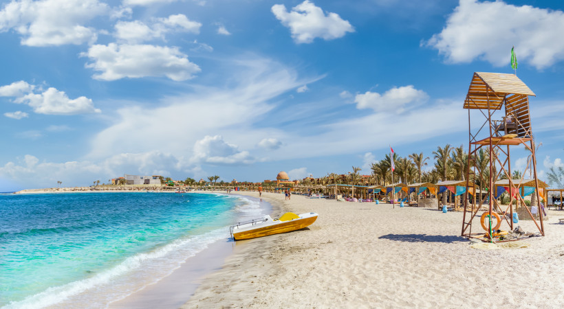 Sandstrand in Marsa Alam mit bunten Sonnenschirmen und Rettungsturm