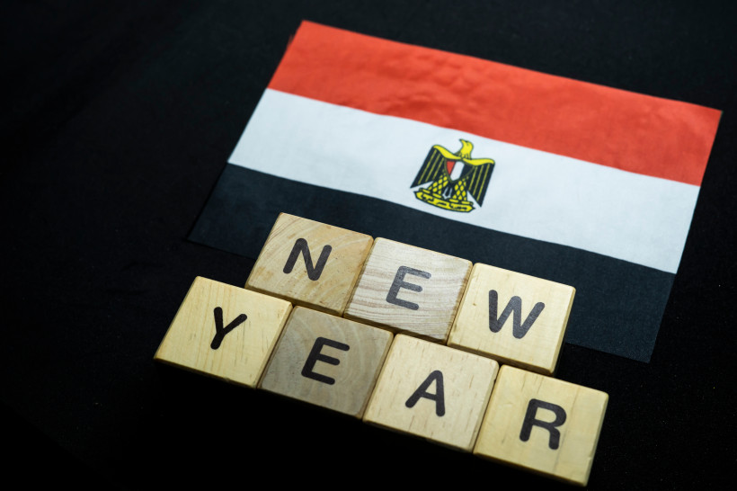 Ägypten - Sharm el Sheikh Ein rechteckiger Ausschnitt zeigt ein kleines ägyptisches Papierfähnchen auf schwarzem Hintergrund. Darunter liegen Holzbuchstaben, die das Wort 'NEW YEAR' bilden.