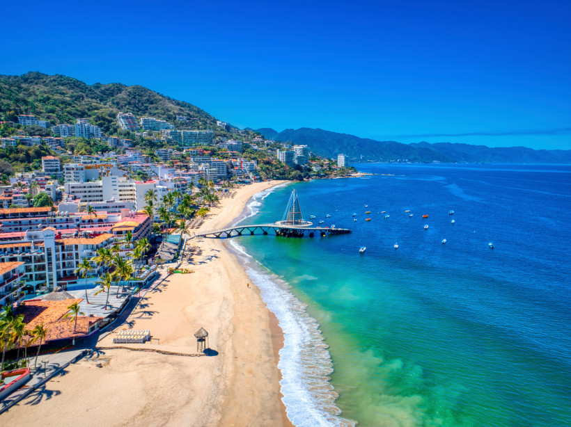 Blick auf Puerto Vallarta an der Pazifikküste Mexikos mit Sandstrand, Palmen, Pier und Hotels – beliebtes Ferienziel 2025/2026