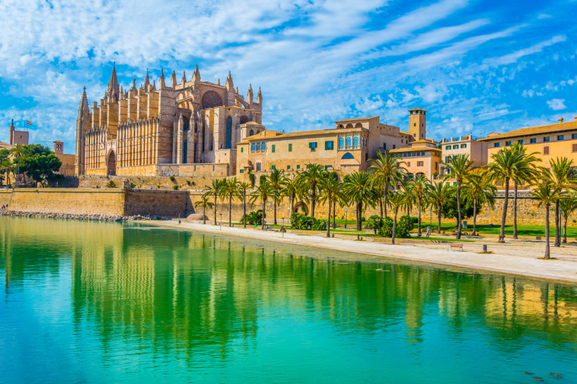 La Seu Kathedrale in Palma de Mallorca am Wasser, mit Palmenpromenade im Vordergrund