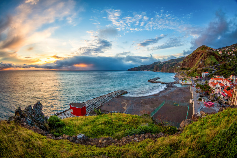Blick auf den Küstenort Ribeira Brava auf Madeira mit Strand, Promenade und Abendstimmung über dem Atlantik