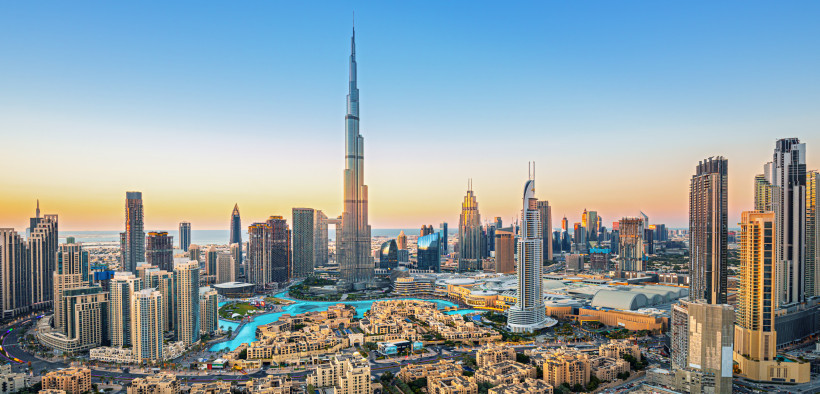 Dubai Panorama der Skyline von Dubai bei Sonnenuntergang mit dem Burj Khalifa im Zentrum. Zahlreiche moderne Hochhäuser und Wasserflächen prägen das Stadtbild.