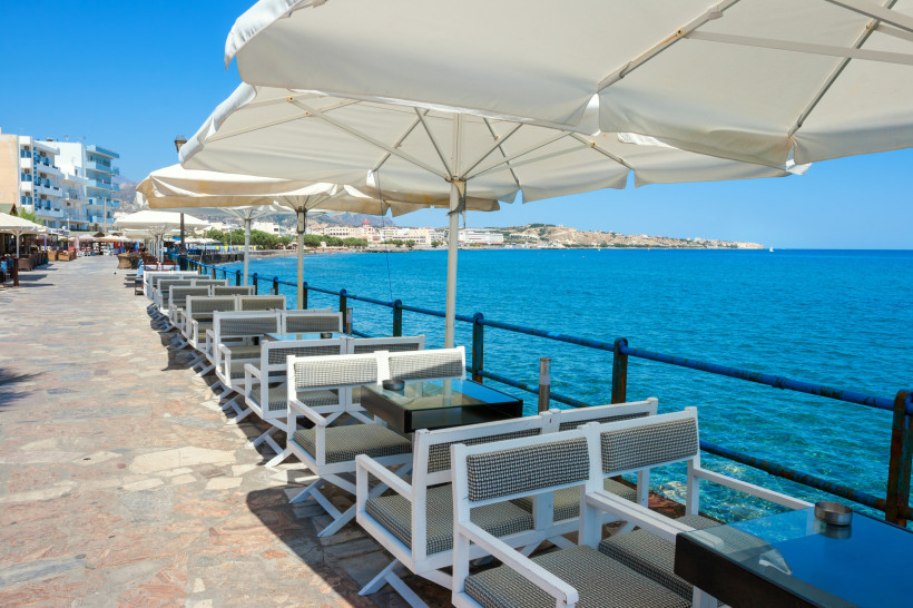 Tische und Stühle einer kleinen Taverne direkt am Wasser in Ierapetra