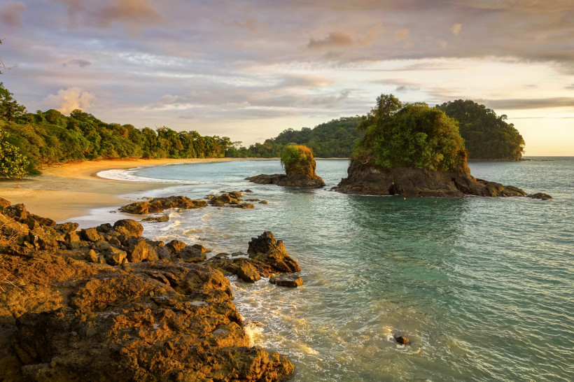 Sonnenuntergang am Strand von Manuel Antonio, Costa Rica Felsküste und Inseln im Manuel Antonio Nationalpark in Costa Rica bei Sonnenuntergang mit goldenem Licht über dem Meer