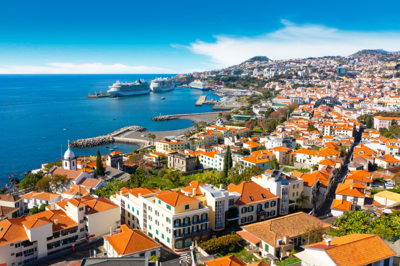 Blick auf den Hafen von Funchal auf Madeira mit Kreuzfahrtschiffen und Stadtbebauung an der Küste