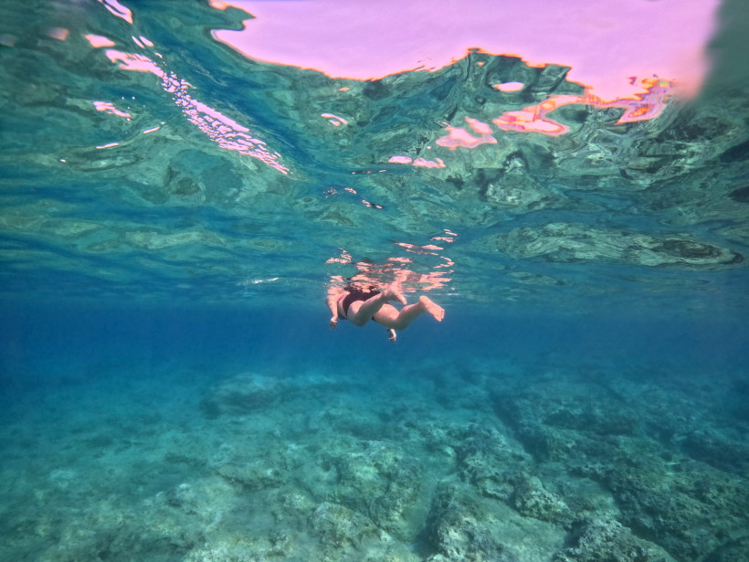 Person schwimmt unter Wasser im klaren Meer der Türkei, ruhige Schnorchelszene mit felsigem Meeresboden und türkisblauem Wasser