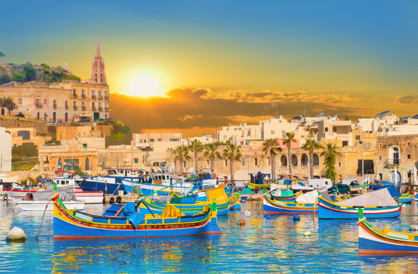 Sonnenuntergang in Marsaxlokk – bunte Luzzus im Hafen von Malta Bunte traditionelle Fischerboote (Luzzus) im Hafen von Marsaxlokk auf Malta bei Sonnenuntergang mit goldener Abendstimmung