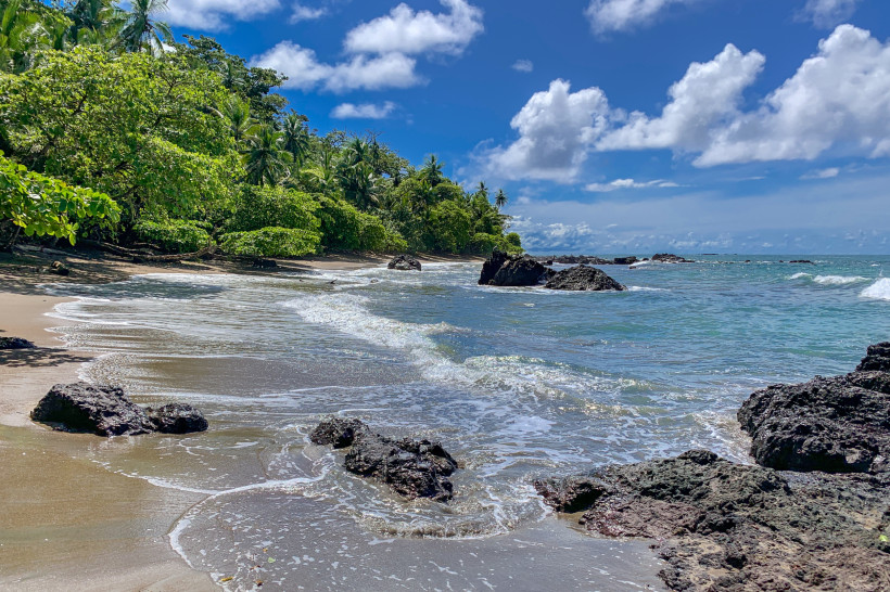 Unberührter Strand an der Pazifikküste von Costa Rica – Naturparadies mit türkisblauem Wasser Unberührter Strand an der Pazifikküste von Costa Rica mit türkisblauem Meer, Felsen und üppiger tropischer Vegetation im Hintergrund