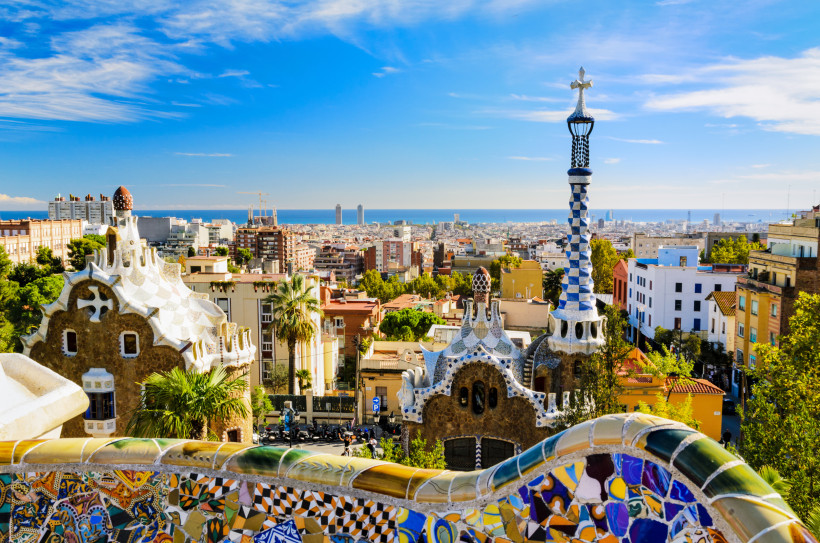 Blick vom Park Güell über Barcelona mit Mosaikbrüstung, Gaudí-Architektur und Mittelmeer am Horizont