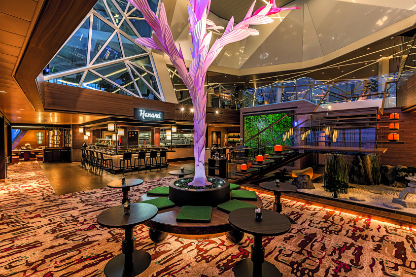 Innenansicht des Restaurants Hanami – By Tim Raue auf der Mein Schiff 6 mit Barbereich, Sitzgruppen und zentraler Baumskulptur