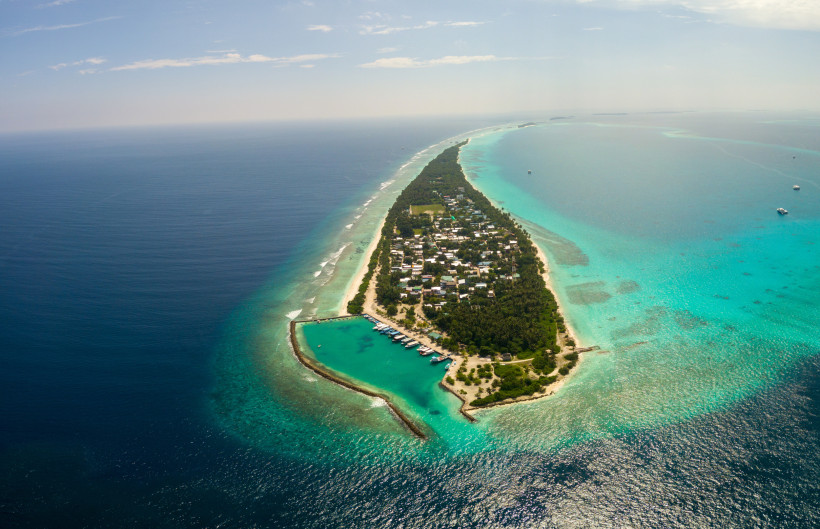 Malediven - Dhigurah (South Ari Atoll) Luftaufnahme einer schmalen bewohnten Insel der Malediven mit Hafen, Häusern und türkisfarbenem Wasser