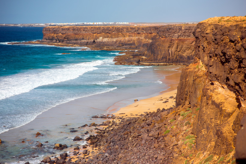 Steilküste an der Westküste bei El Cotillo mit Wellen, Sandstrand und Felsen