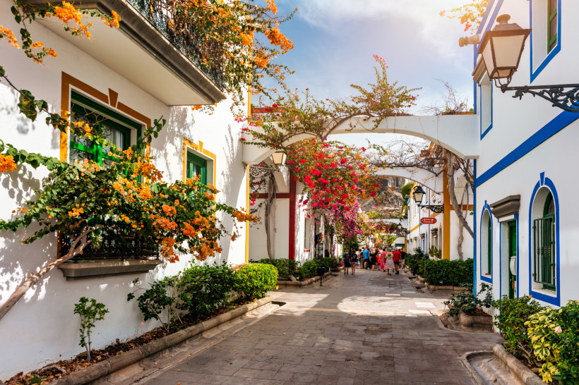 Gasse in Puerto de Mogán auf Gran Canaria mit weißen Häusern, bunten Fensterrahmen und blühender Bougainvillea