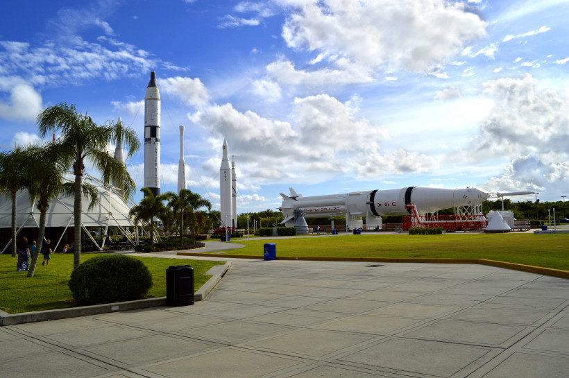 Raketenexponate im Außenbereich des Kennedy Space Center vor blauem Himmel