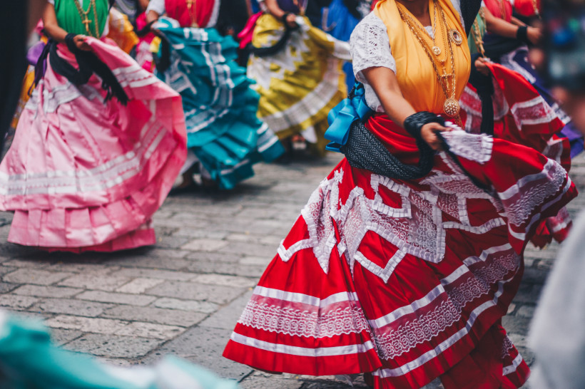Festival in Oaxaca Gruppe von Tänzerinnen in traditionellen, bunten mexikanischen Kleidern mit Rüschen und Spitze, die während einer folkloristischen Tanzaufführung schwungvoll ihre Röcke schwingen
