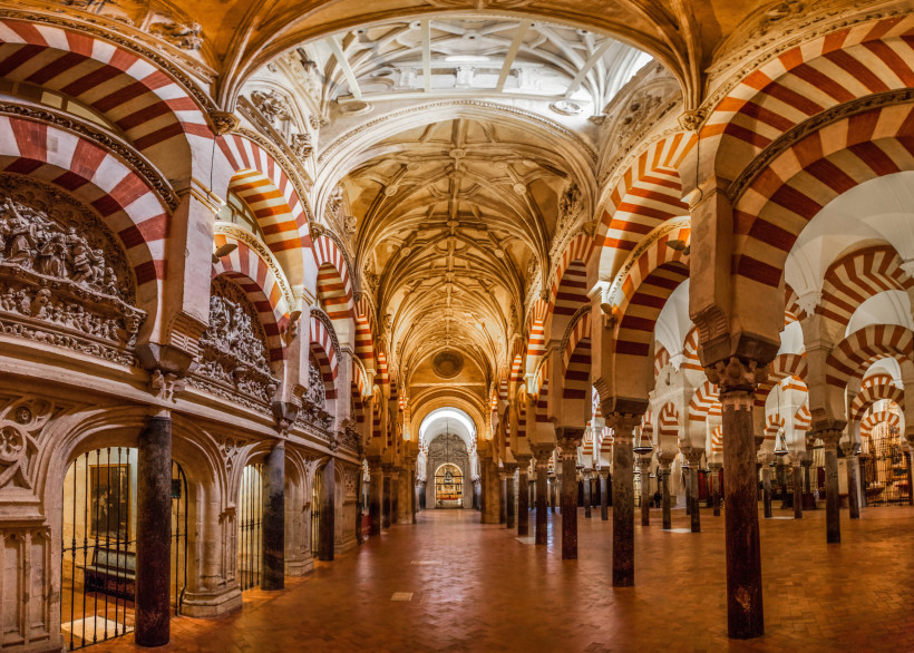 Innenraum der Mezquita in Córdoba mit rot-weiß gestreiften Hufeisenbögen und Säulenreihen