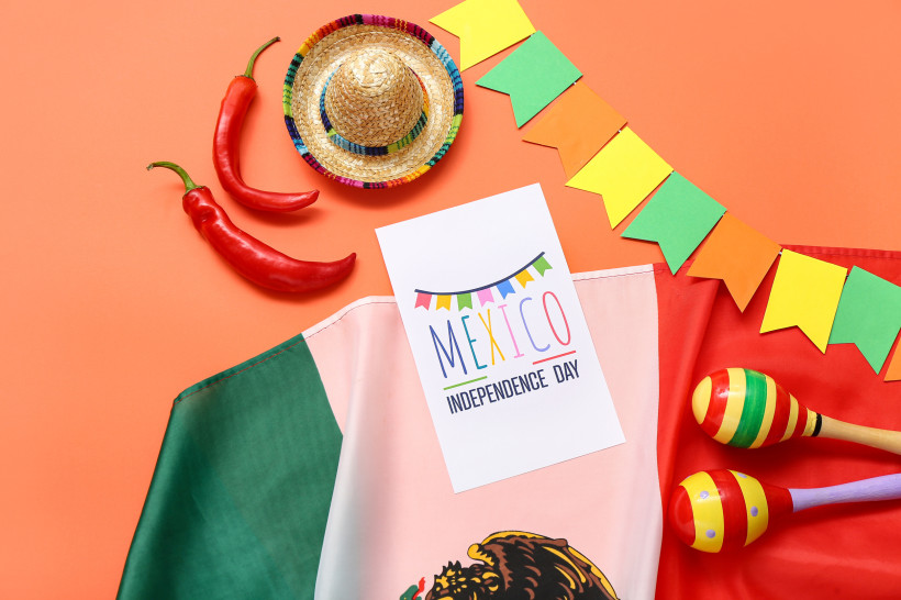 Mexiko Grußkarte mit Text MEXIKO UNABHÄNGIGKEITSTAG, mexikanische Flagge, Maracas und Sombrero auf orangefarbenem Hintergrund