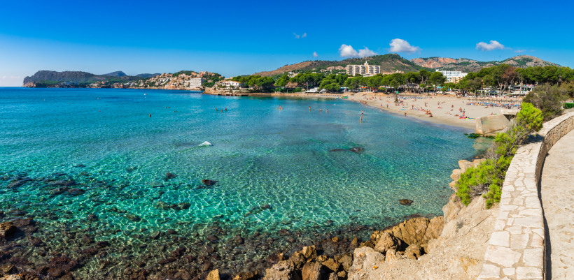 Bucht und Sandstrand Platja de Tora in Peguera mit klarem Wasser, Badegästen und Hotels im Hintergrund