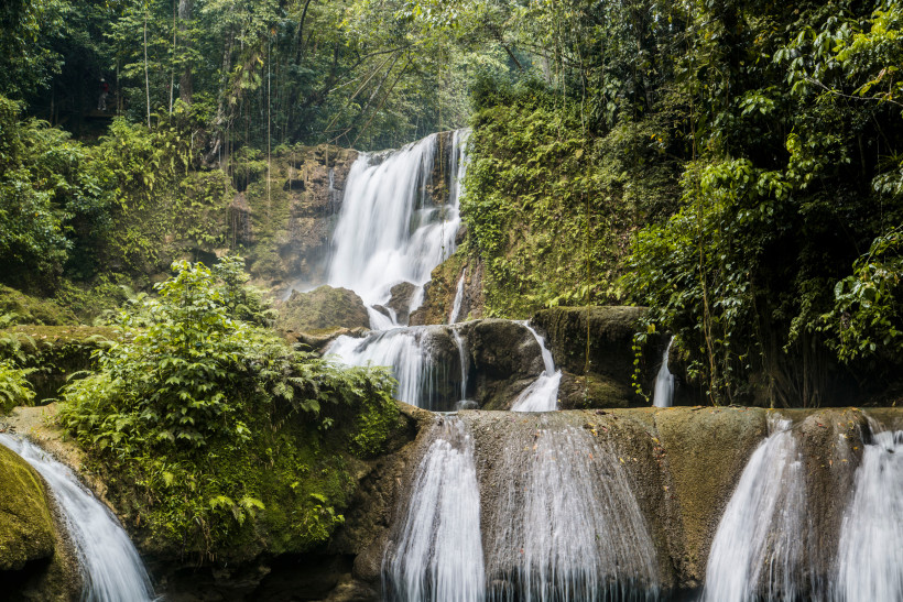 Spektakulärer Wasserfall im tropischen Regenwald – Naturparadies mit üppiger Vegetation Mehrstufiger Wasserfall im tropischen Regenwald – üppige Vegetation und moosbewachsene Felsen umgeben das herabstürzende Wasser.