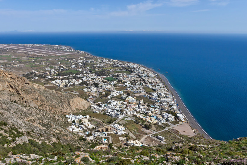 Santorini - Kamari  Kamari auf Santorini vom Mesa Vouno aus: Küstenort mit langem schwarzem Lavastrand, Häusern am Fuß des Berges und weitem Blick über die Ägäis