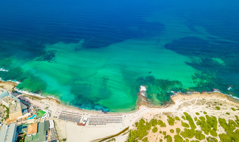 Luftaufnahme des Playa de Can Picafort mit breitem Sandstrand, Liegenbereichen und flachem Meer