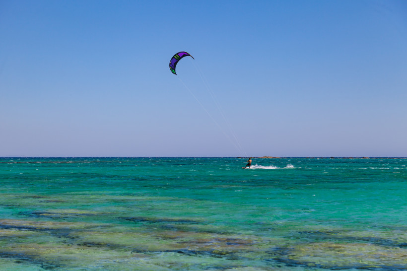 Kitesurfer auf türkisfarbenem Meer vor der Nordküste Kretas bei Malia