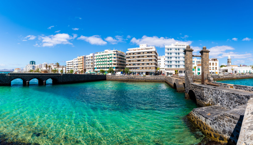 Arrecife Altstadt mit Puente de las Bolas – historische Brücke und türkisfarbenes Meer auf Lanzarote Historische Puente de las Bolas in Arrecife vor türkisblauem Wasser mit Stadtpanorama und Altstadt im Hintergrund auf Lanzarote.