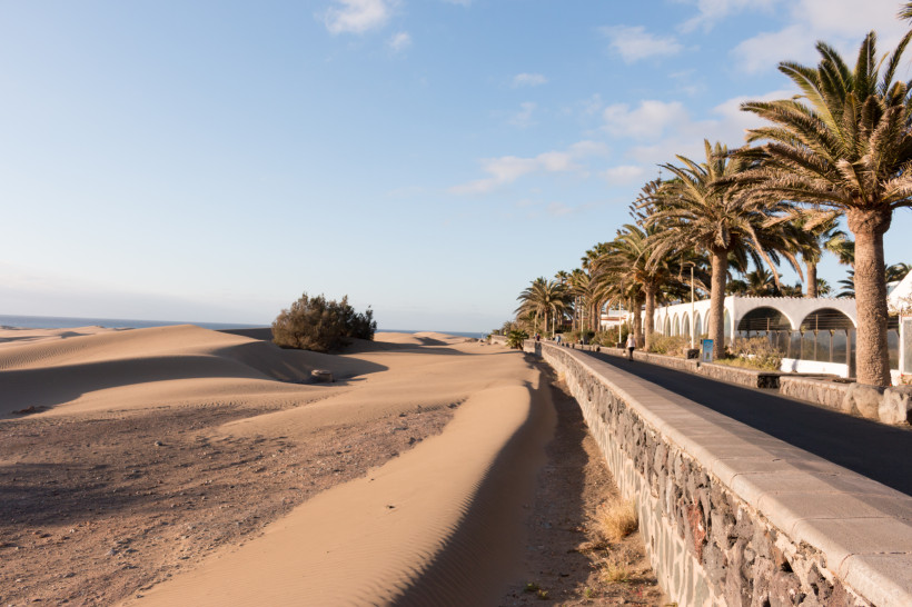 Sanddünen an der Playa del Inglés mit Palmenpromenade und Steinmauer