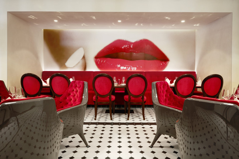 Restaurantbereich „French Kiss“ auf der AIDAprima mit roten Polsterstühlen und Wandmotiv mit Lippen