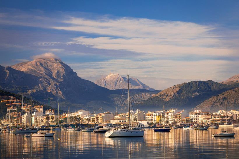 Hafen von Port de Pollença mit Segelbooten, Uferbebauung und Bergen im Hintergrund