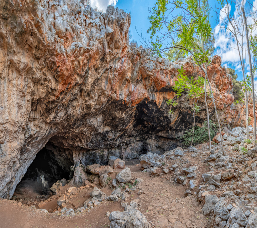 Höhle von Skotino: Höhleneingang in einer Felswand Eingang der Höhle von Skotino in einer felsigen Kalksteinwand mit Geröll und schmalem Pfad