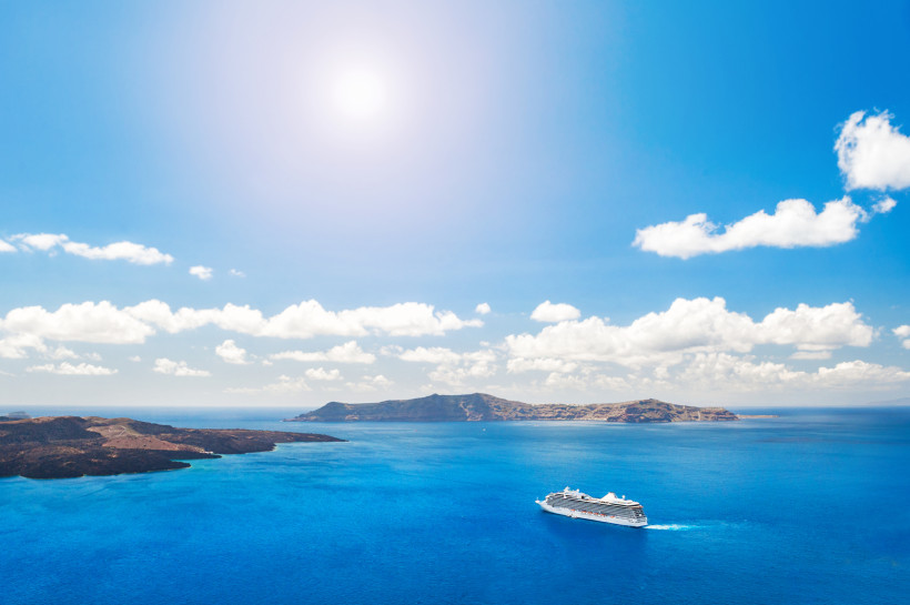 Kreuzfahrtschiff auf dem Mittelmeer vor einer Inselküste bei Sonnenschein