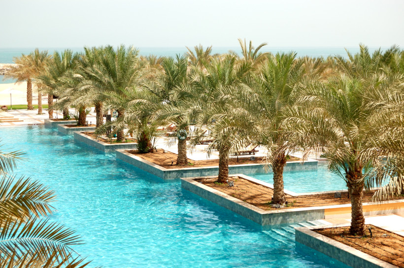 Ras al Khaimah, Luxusurlaub Luxuriöser Pool mit Palmeninseln, klarem Wasser und Blick auf das Meer