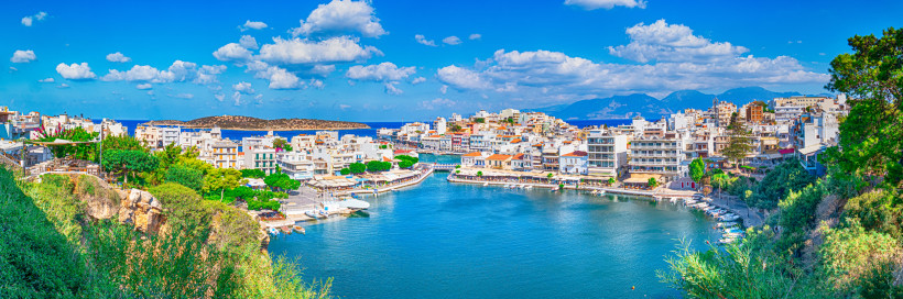 Blick auf den Hafen von Agios Nikolaos mit Uferpromenade, Booten und Häusern am Wasser