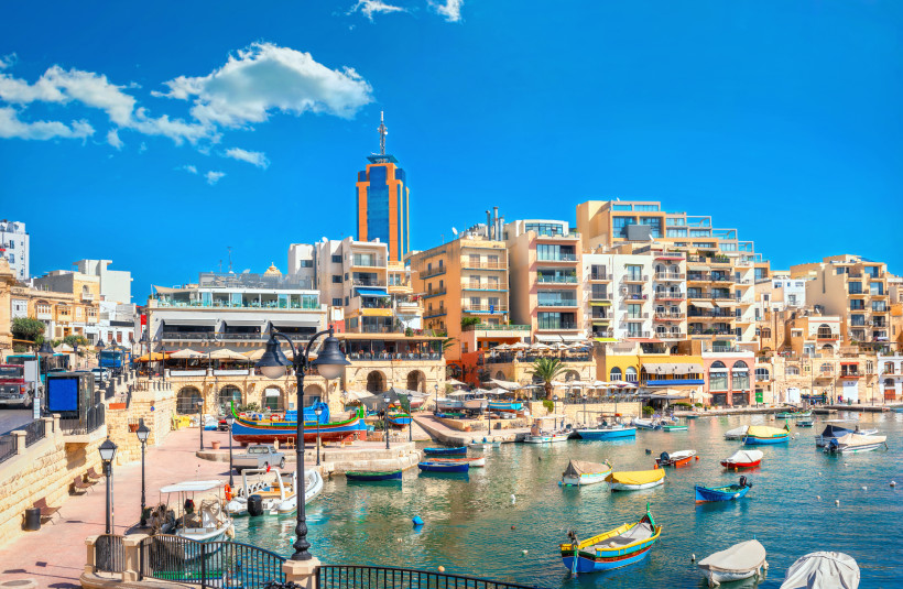 St. Julian’s Malta – Spinola Bay mit bunten Booten und moderner Skyline Spinola Bay in St. Julian’s auf Malta mit bunten Fischerbooten, modernen Gebäuden und Restaurants am Wasser
