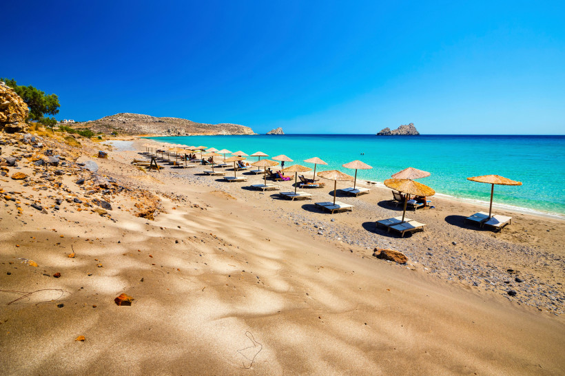 Strand von Xerokambos mit Sonnenliegen und Strohschirmen am türkisfarbenen Meer