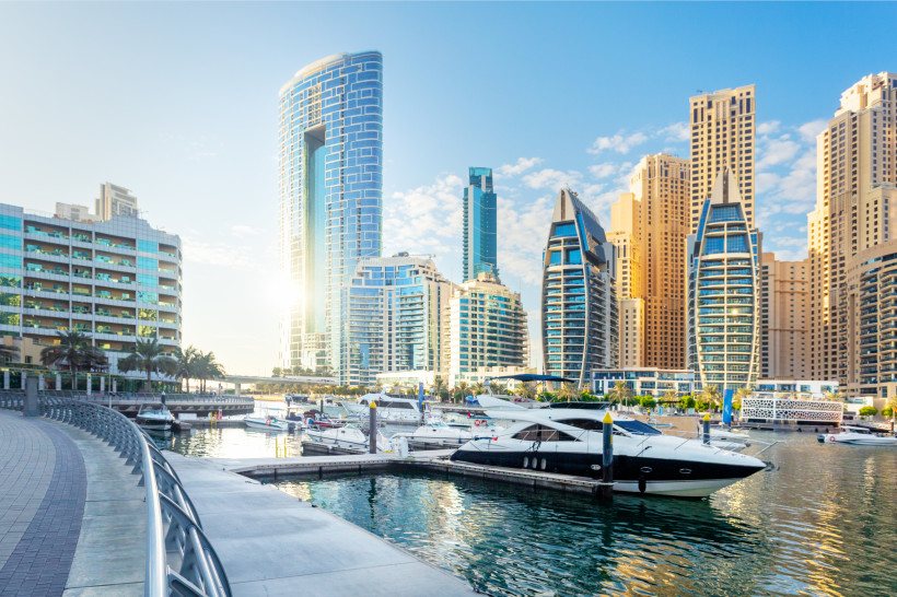 Dubai Marina mit Yachthafen, festgemachten Motorbooten und Hochhäusern im Hintergrund