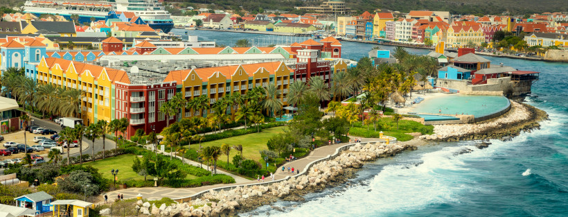 Uferpromenade und Küstenpark in Willemstad, Curaçao, mit farbigen Gebäuden, Palmen und Blick auf den Hafen