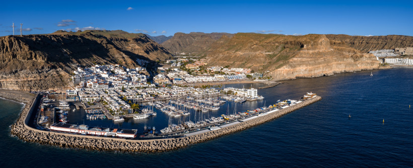 Blick auf den Hafen und die Marina von Puerto de Mogán auf Gran Canaria mit weißen Gebäuden, Booten und umliegenden Felsbergen