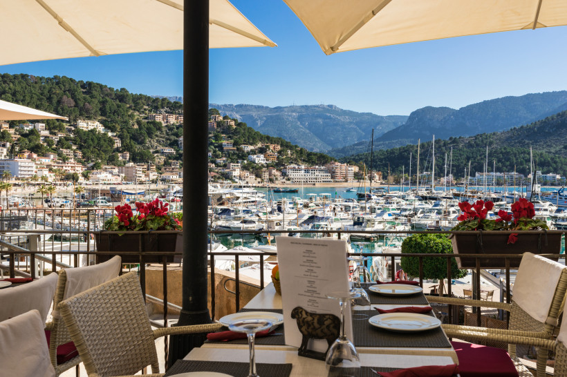 Terrasse eines Restaurants mit Blick auf den Yachthafen von Port de Sóller und die umliegenden Berge